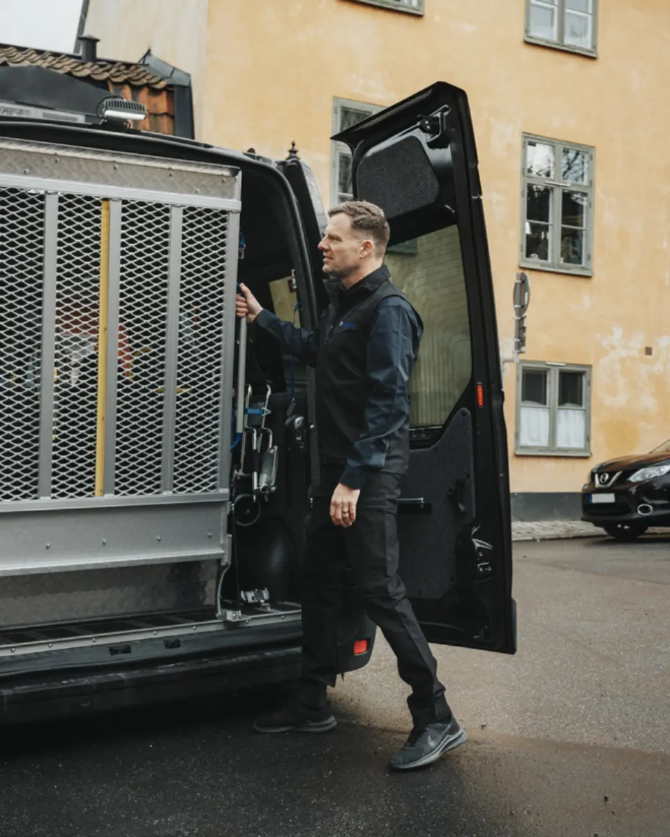 Förare i mörk väst och skjorta öppnar bakdörrarna på en minibuss med rullstolslift